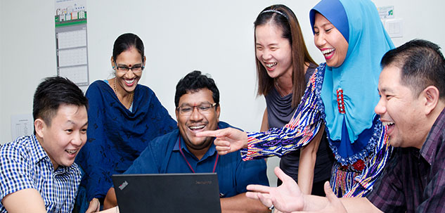a team laughing behind a laptop screen
