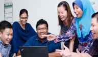 a team laughing behind a laptop screen